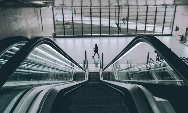 grayscale photography of person walking near escalator